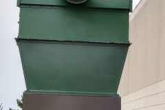 Slant screen separator mounted on top of a compactor outside of the building.